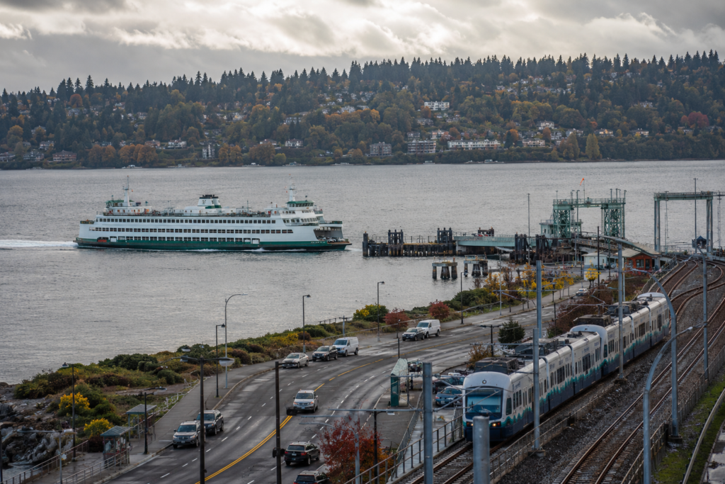 Balsa, trem leve e rodovia no Puget Sound, ilustrando a integração entre diferentes meios de transporte na região de Washington.