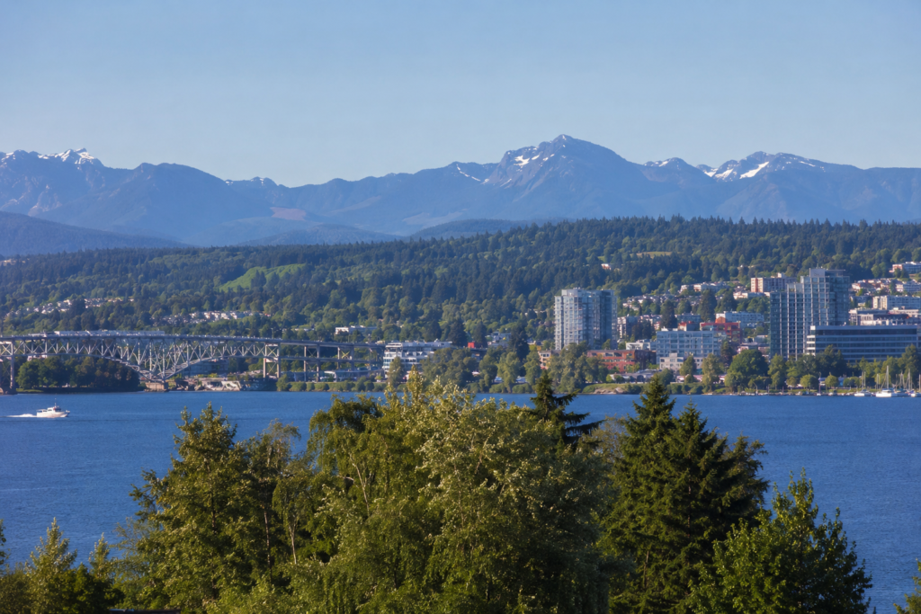 Vista panorâmica da região do Puget Sound, com águas costeiras, áreas urbanas, colinas arborizadas e montanhas ao fundo no estado de Washington.