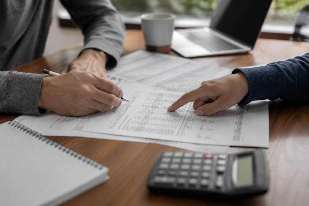 Mesa de escritório com documentos fiscais, calculadora e computador portátil, representando a comparação entre o Social Security Number (SSN) e o Individual Taxpayer Identification Number (ITIN) nos Estados Unidos.