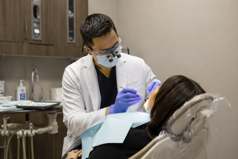 Dentista realizando atendimento odontológico em paciente reclinada em uma clínica nos Estados Unidos.