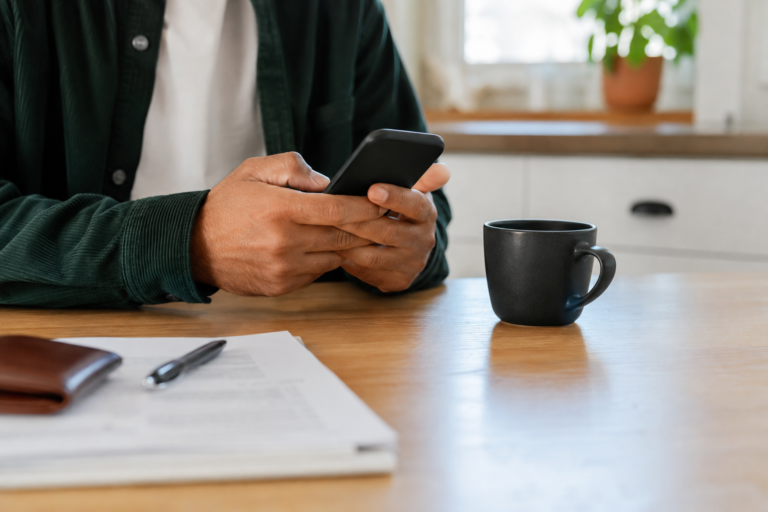 Pessoa utilizando um smartphone em uma mesa enquanto consulta informações bancárias relacionadas ao depósito direto do salário nos Estados Unidos.