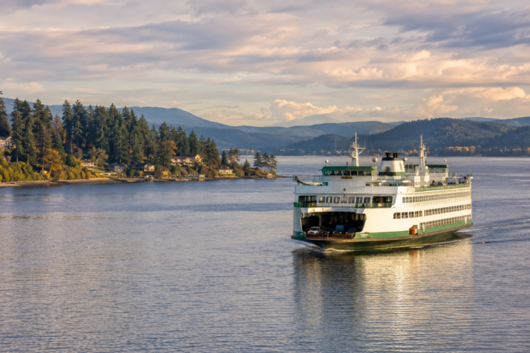Balsa navegando pelas águas do Puget Sound, no Estado de Washington, com ilhas arborizadas e montanhas ao fundo.