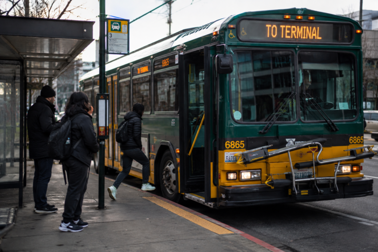 Ônibus de transporte público parando em um ponto de embarque no centro urbano da região do Puget Sound.