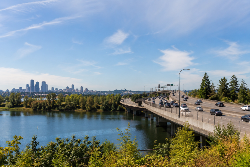 Faixa HOV em uma rodovia de Washington com vários veículos circulando sobre uma ponte, água e paisagem urbana ao fundo.