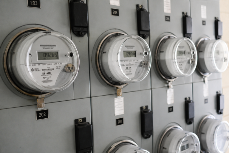 Medidores individuais de eletricidade instalados em um prédio residencial, representando a cobrança de utilities associada a diferentes unidades de aluguel.