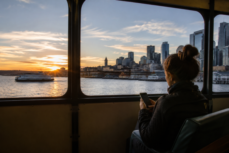 Passageira dentro de uma balsa observa a região de Seattle pela janela durante uma viagem de transporte público.