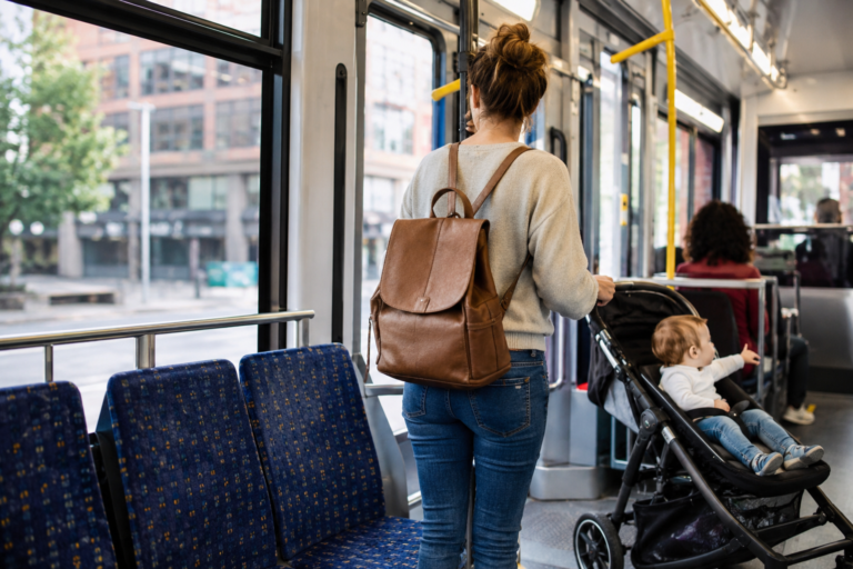 Interior de transporte público com passageira acompanhando uma criança em carrinho de bebê, mostrando como o equipamento pode ser levado durante a viagem.