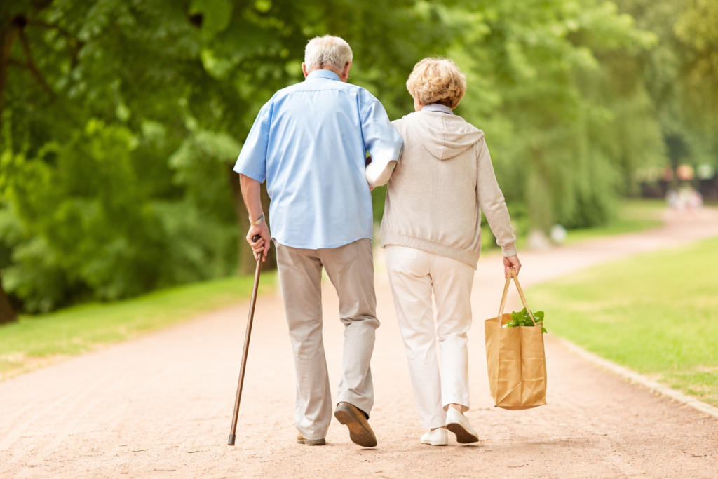 Diferença entre Medicare e Medicaid representada por um casal de idosos caminhando em um parque, ilustrando a principal faixa etária associada ao Medicare e o tema da assistência à saúde nos Estados Unidos.