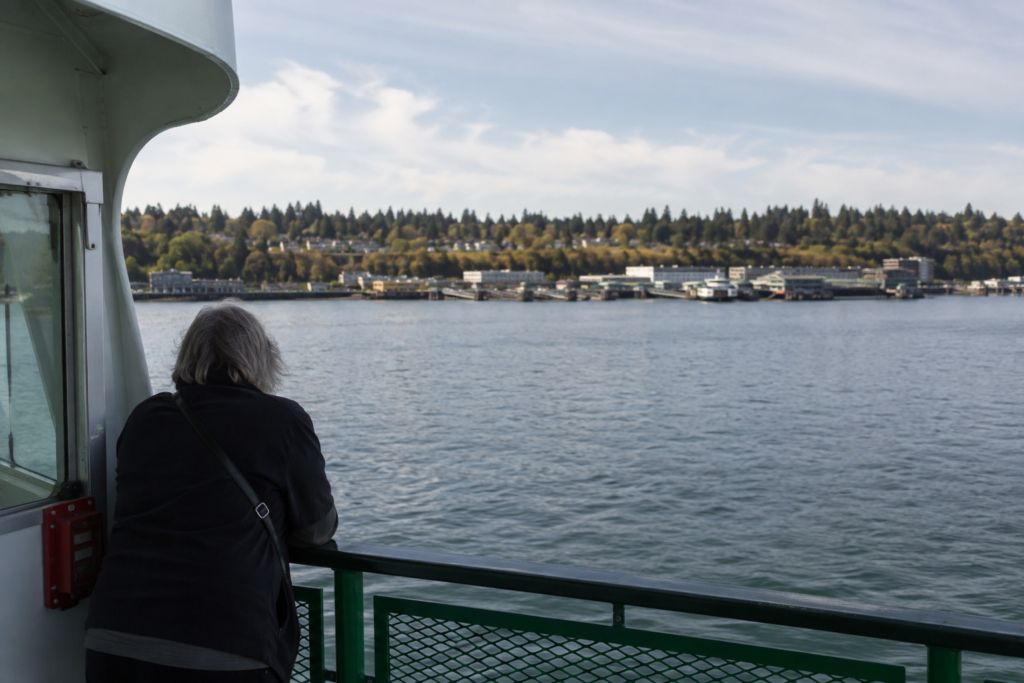Vista de Bainbridge Island a partir de uma balsa, com o litoral arborizado e a área urbana de Winslow ao fundo.