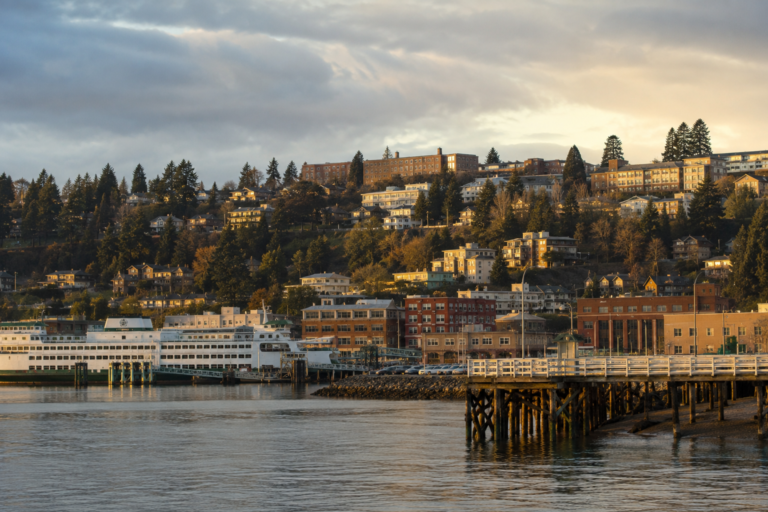 Bremerton vista a partir da orla, com terminal de ferry, águas de Sinclair Inlet e bairros urbanos distribuídos pelas encostas da cidade.