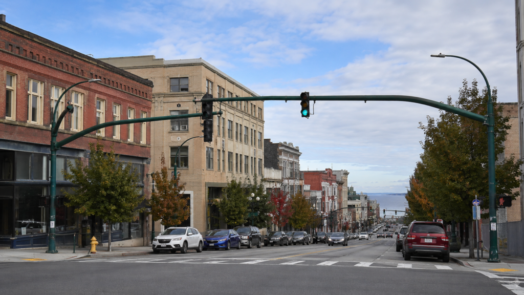 Hewitt Avenue no centro de Everett, com edifícios históricos, trânsito urbano e Port Gardner ao fundo.