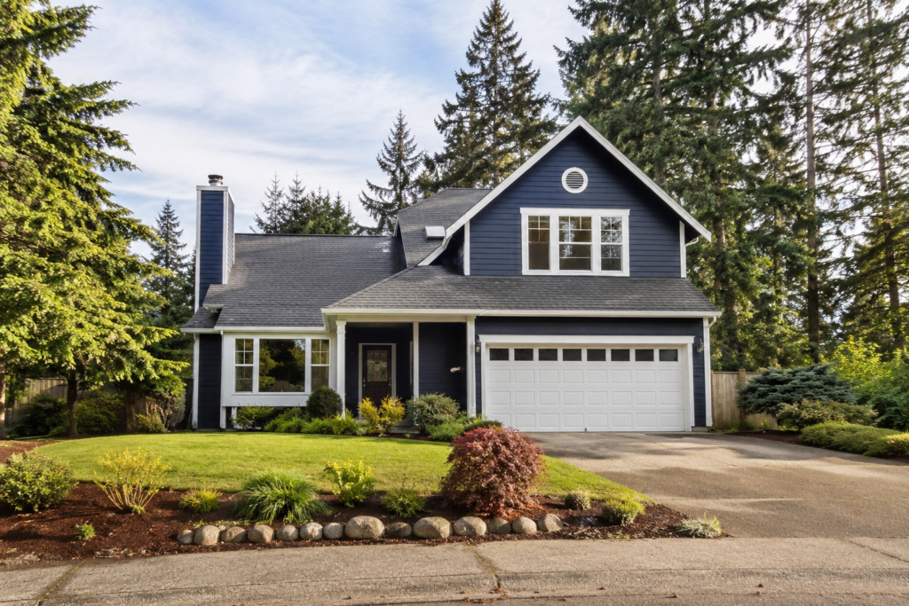 Uma casa unifamiliar com garagem, jardim e quintal em um bairro residencial arborizado da região do Puget Sound.