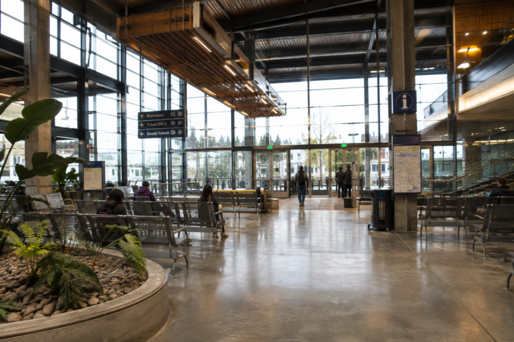 Área interna de um Transit Center moderno, com assentos, passageiros e espaços de conexão entre diferentes serviços de transporte público.
