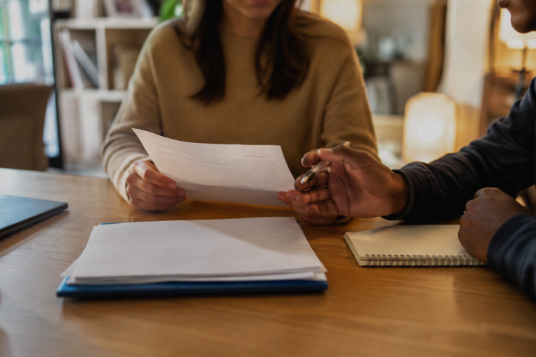 Duas pessoas analisando documentos de um contrato de aluguel sobre uma mesa, representando a participação de um co-signer nas obrigações financeiras da locação.