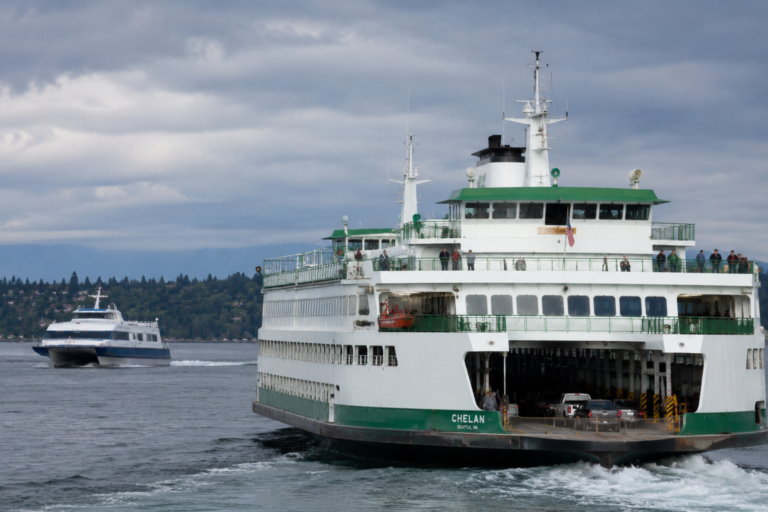 Washington State Ferry transportando veículos em Puget Sound, com uma embarcação rápida de passageiros navegando ao fundo.